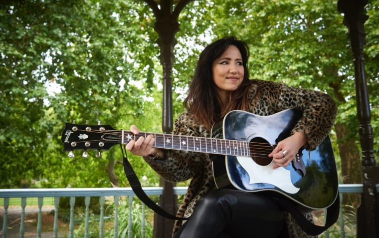 Picture of KT Tunstall playing guitar in a park
