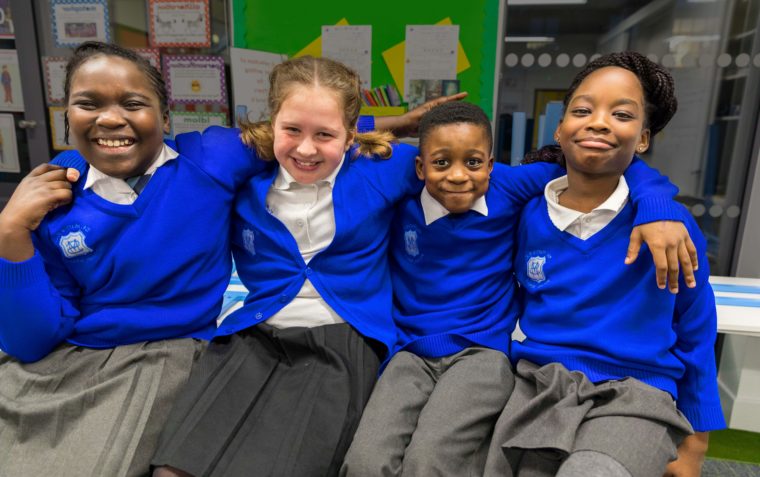 Four Primary School Pupils sitting closer to each other and smiling