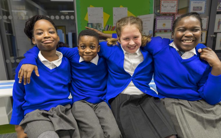 Four Primary School Pupils sitting closer to each other and smiling