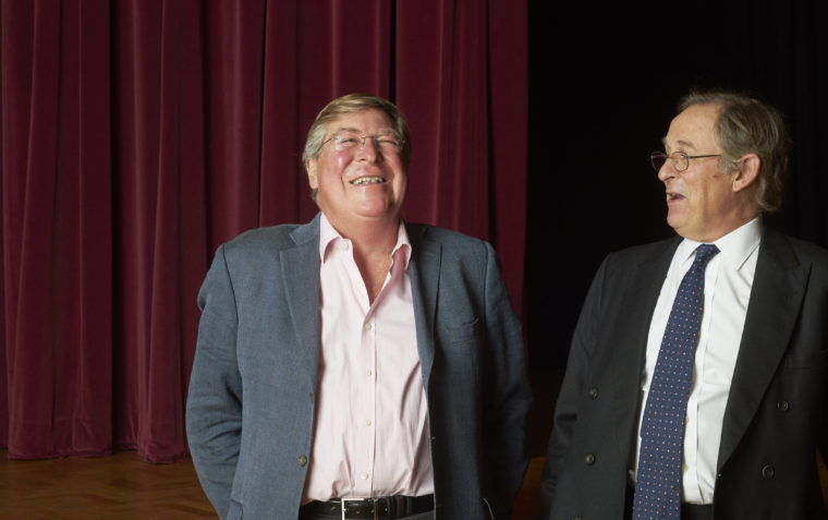 A photograph of Ed Stourton and Sir Nicolas Mostyn standing inside a theatre and laughing.