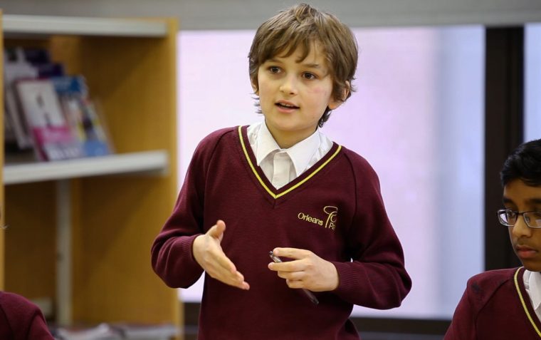 A student explaining his point of view/giving an answer to a question while his peers listen to him