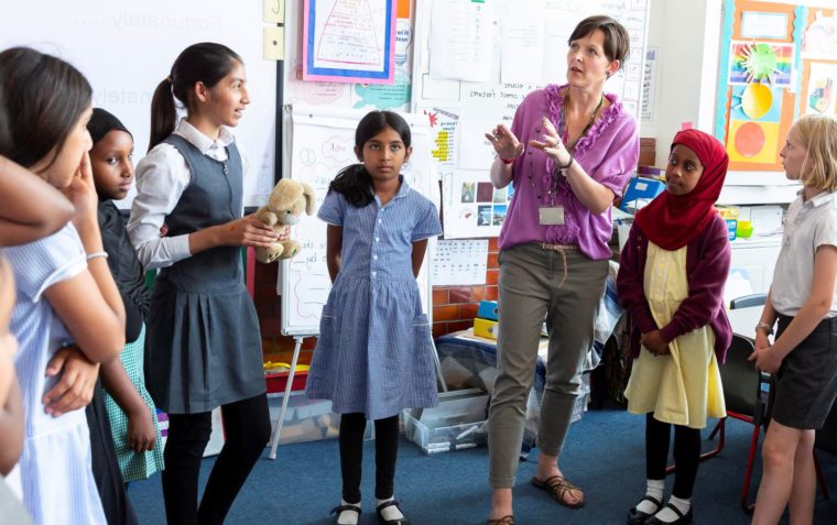 Liezel Closer is speaking to primary school pupils inside a classroom and listening to the tutor speaks.