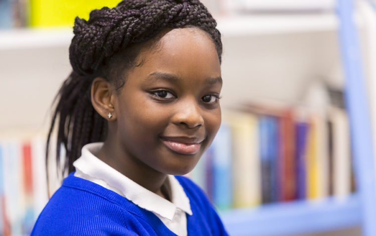 A clos-up of a young girl pupil sitting inside a classroom.