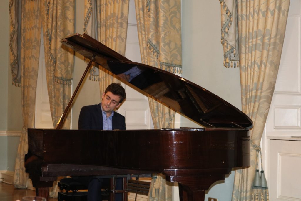 A male pianist playing a piano.