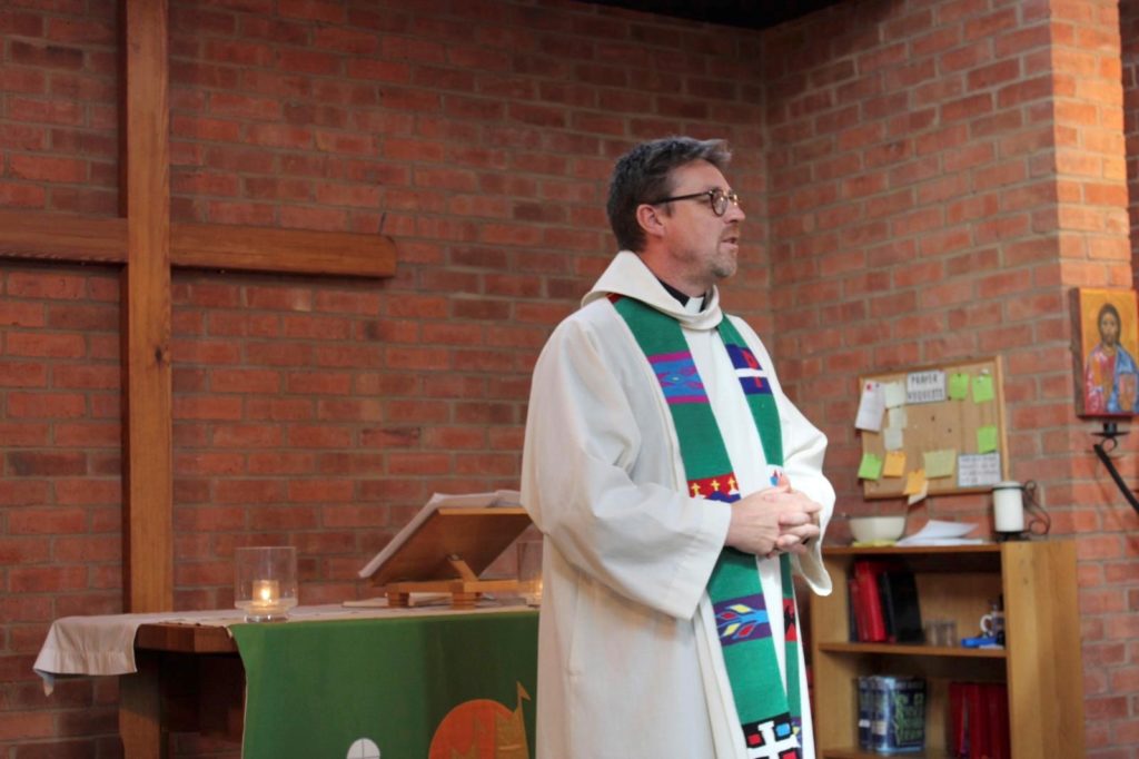 A picture of a vicar standing in front of an altar.