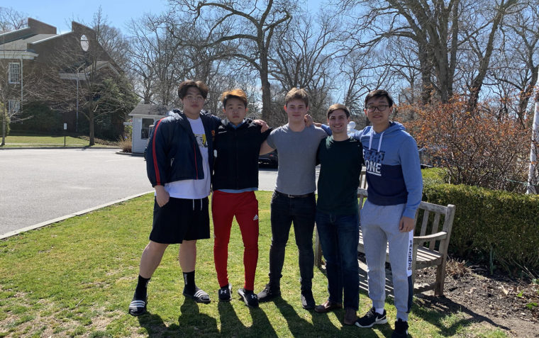 A group of 5 students posing for a photo in a lawn