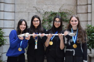 The 4 girls who are the schools' mace debating competition winners holding the mace