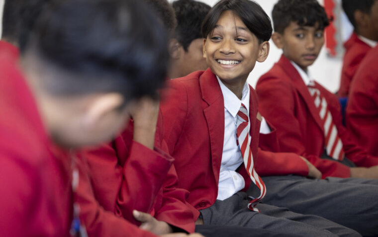 Young boys in red school uniforms sat together, facing each other smiling