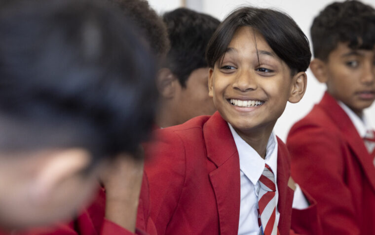 Young boys in red school uniforms sat together, facing each other smiling