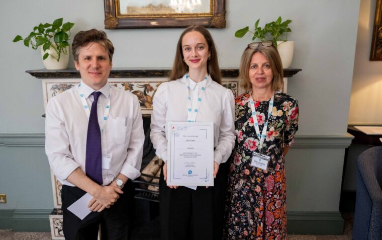 Woman with a certificate standing with a man to her left and a woman to her right