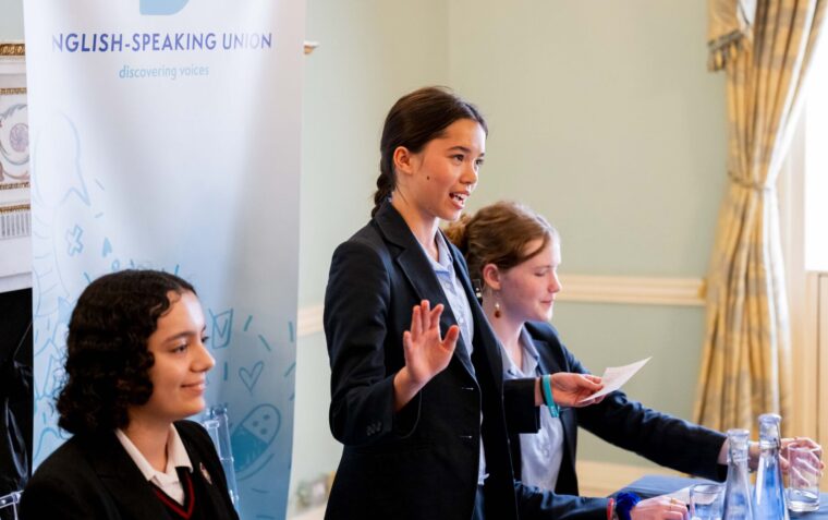 Young lady with dark hair speaking passionately, surrounded by her two teammates