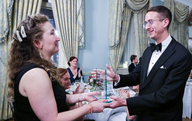 Man receiving award from woman at a gala style event