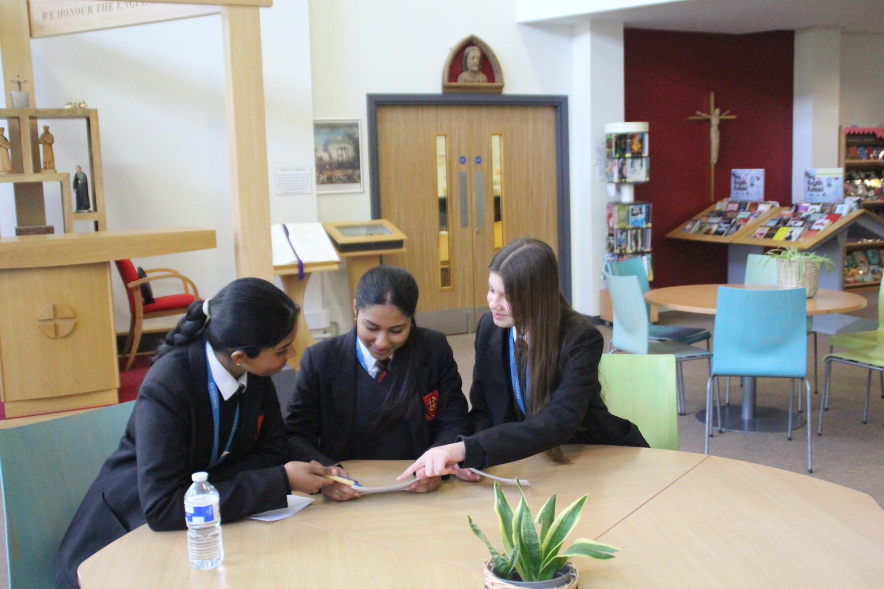 Three schoolgirls sat at a table, discussing their work